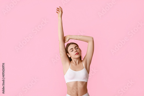 Beautiful young woman after epilation of armpits on pink background photo