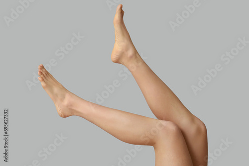 Legs of beautiful young woman after depilation on grey background