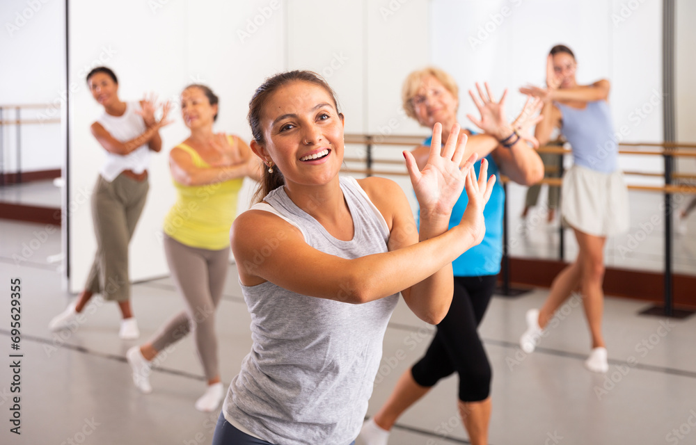 Dancing latin american woman, engaged in a group class in the studio, practices an energetic swing