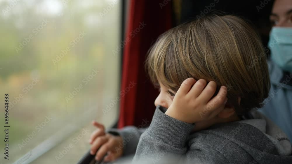 Passenger child traveling by train staring at parallel train pass by inside high speed transportation. Thoughtful little boy with hands in chin daydreaming while travel Passenger child traveling by train staring at parallel train pass by inside high speed transportation. Thoughtful little boy with hands in chin daydreaming while travel
