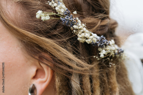 Close-up view of bride's hairstyle with dreadlocks and flowers.