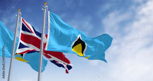 Saint Lucia national flags waving with United Kingdom flag on a clear day photo