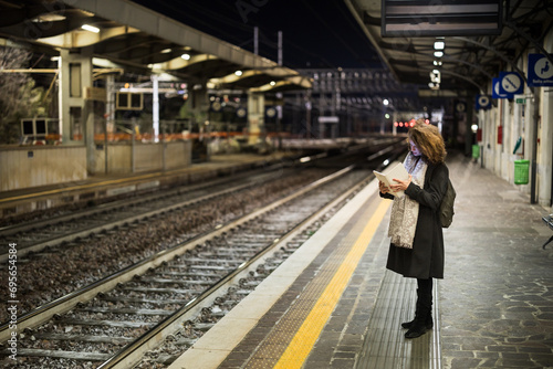 Adult Woman Tourist Using Tablet at Railway Station While Waiting Alone for Train in Early Morning © Fotopogledi
