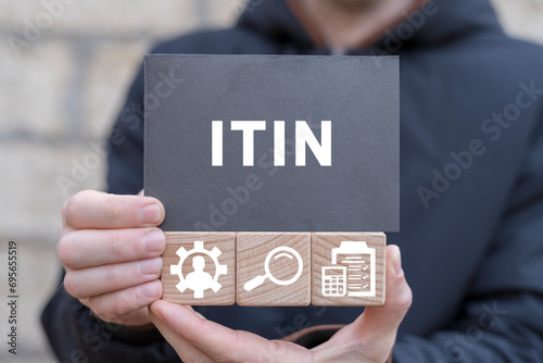 Man holding wooden cubes with icons and black sticky note with acronym: ITIN. ITIN - Individual Taxpayer Identification Number Business concept. photo