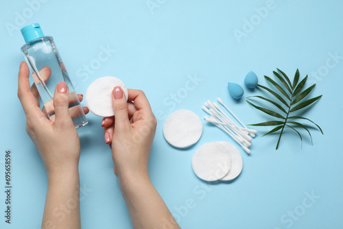 Woman with makeup remover, sponges, cotton pads and buds on light blue background, top view photo