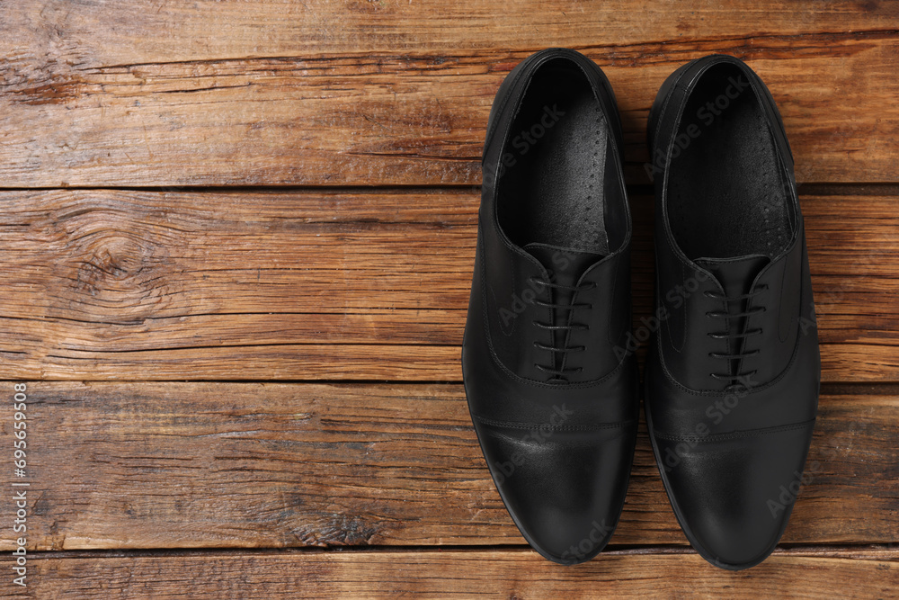 Pair of black leather men shoes on wooden background, top view. Space for text Pair of black leather men shoes on wooden background, top view. Space for text