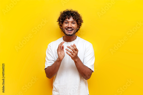 young indian guy laughing and cheering looking at the camera on a yellow isolated background