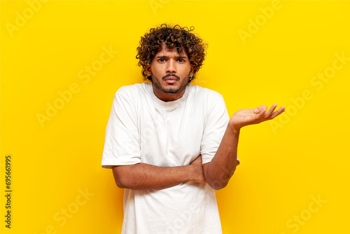 Cuadro en lienzo young indian uncertain guy doesn't know and shrugs over yellow isolated backgrou
