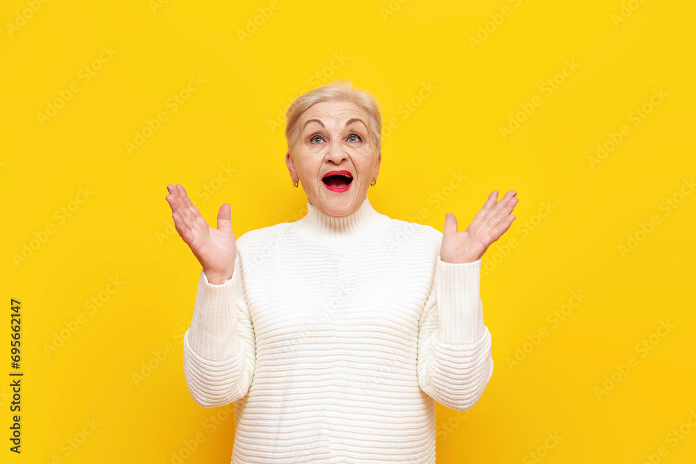 shocked old granny in a white sweater wonders with her mouth open over yellow isolated background shocked old granny in a white sweater wonders with her mouth open over yellow isolated background
