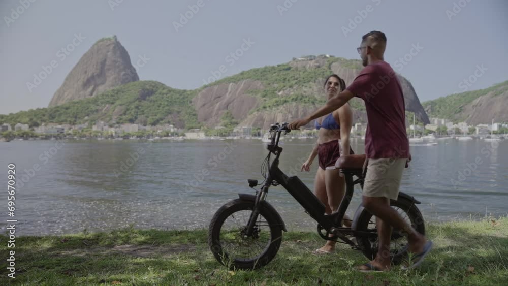 Jovem casal caminhando pela costa, conversando, empurrando uma bicicleta. Cinematico 4k.