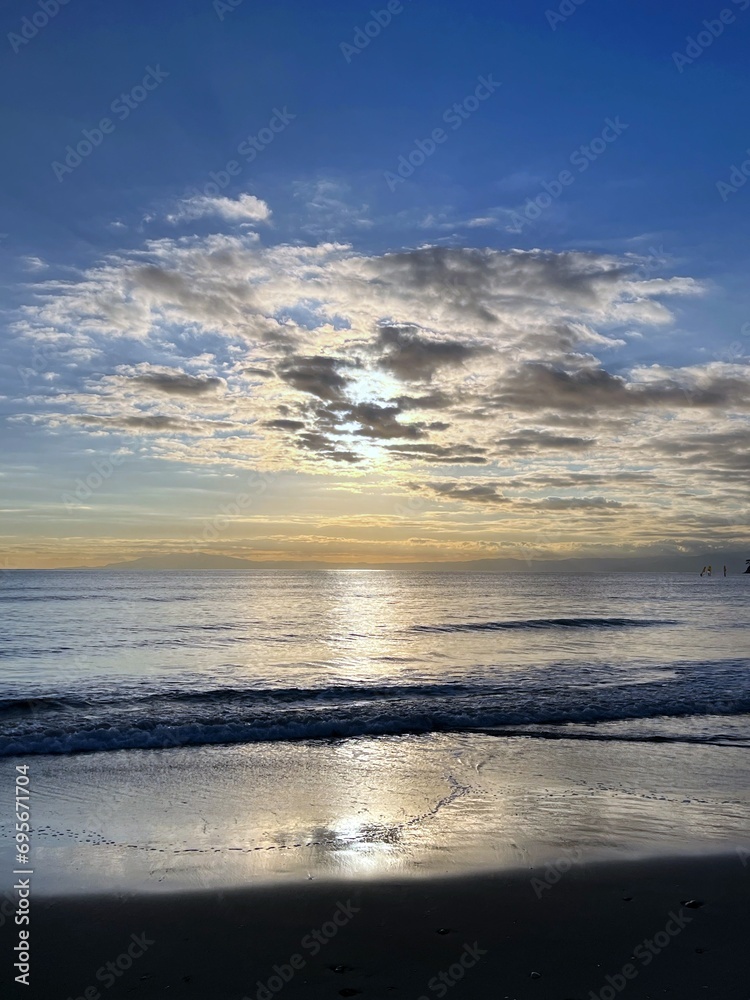 Fototapeta premium 美しい海岸の夕焼け、光る海と沈む太陽、光る海と青い空の太陽、銀色の海と青い空、夕暮れ時の海の風景