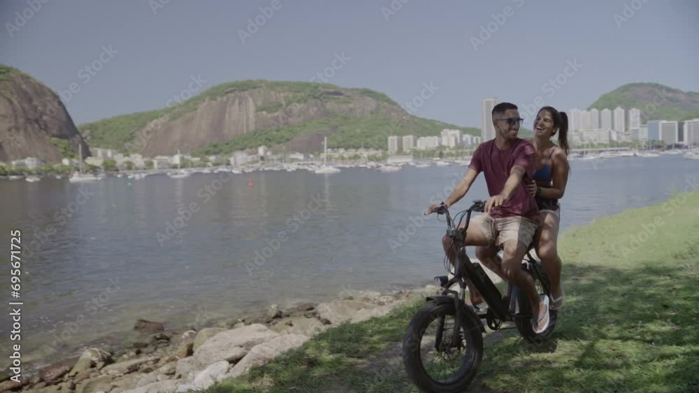 Jovem casal se divertindo andando de bicicleta ao longo da costa. Cinematico 4k.