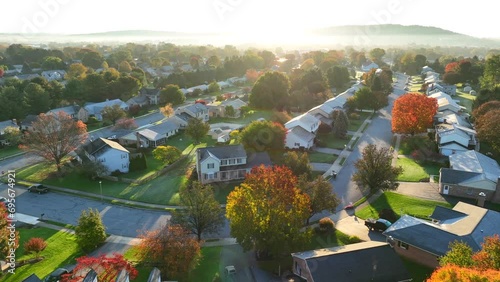Bright sunrise over American neighborhood during autumn morning. Aerial shot of houses and homes in suburb. photo