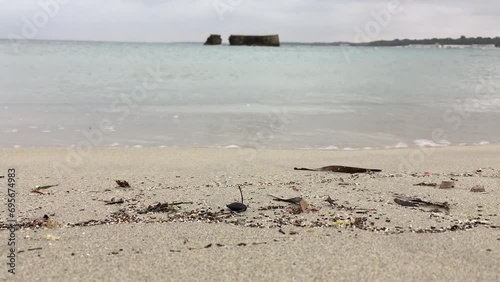 Sand beach in San Cataldo, Italy near lecce city with brick wall on island in the background in slow-motion