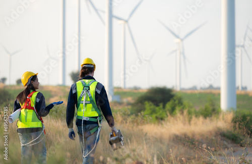 Engineer and worker discussing on a wind turbine farm with blueprints