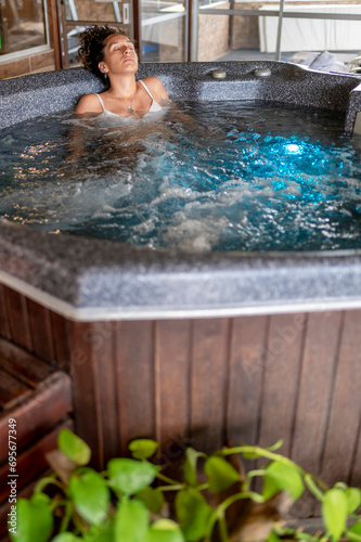 Mixed race woman relaxing in a hot tub during a spa day.