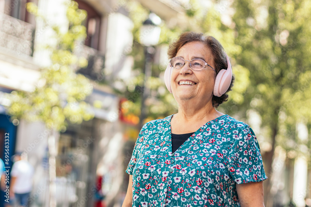 Senior woman walking down the street listening to music