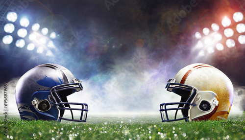 two American football helmets facing each other on football field with stadium lights