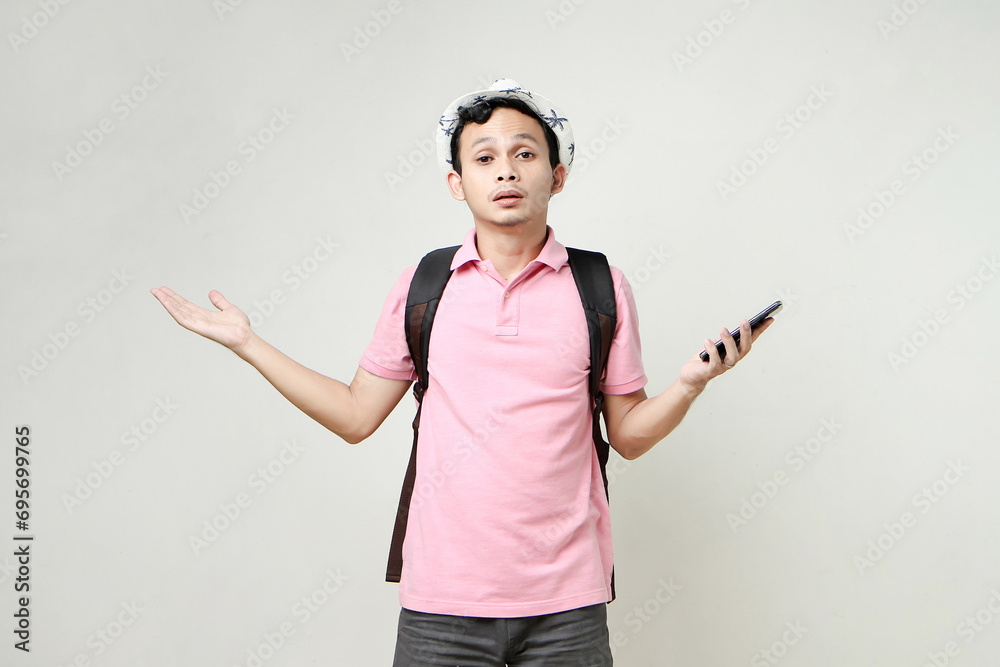Asian man backpacker hold mobile phone with confused expression. travelling concept. on isolated background Asian man backpacker hold mobile phone with confused expression. travelling concept. on isolated background