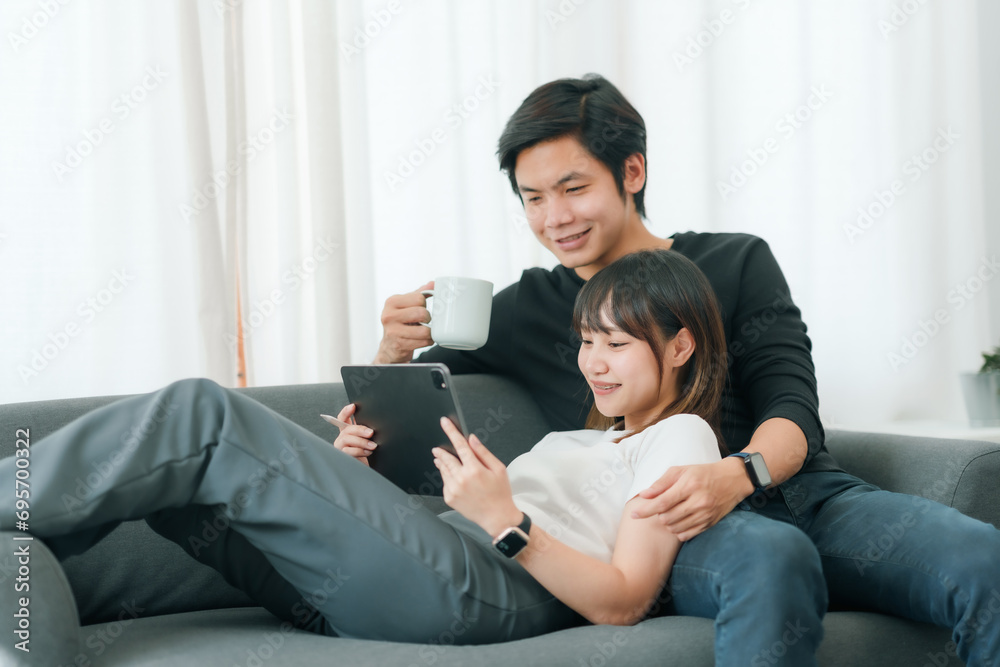 Young Asian couple in love using tablet together at home. Young Asian couple in love using tablet together at home.