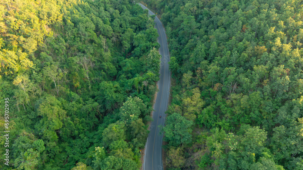 Aerial view of road dark green forest Natural landscape and elevated traffic roads Adventure travel and transportation ideas for the environment
