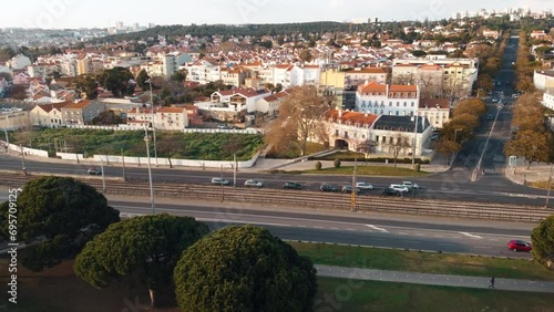 Aerial rotating view of a residential area on the opposite side of Torre Bellem in Lisbon, Portugal. The scene includes a highway with flowing car traffic, low-angle sunlight, high-quality 4K. photo