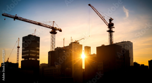 New construction site with crane and mechanical equipments on sunset background. Construction site crane. Silhouette building site.