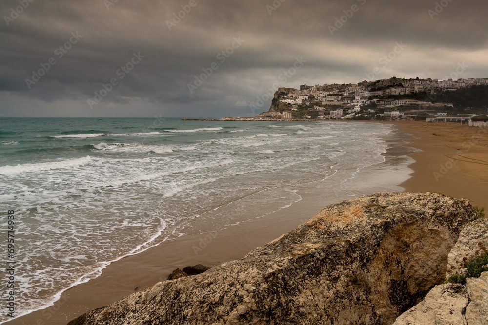 view of Peschici Bay and clifftop town under a rainy and overcast sky
