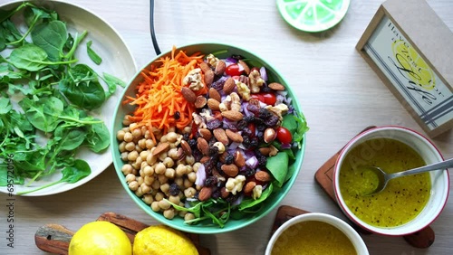Aerial top view of chick peas salad assorted nuts tomatoes carrots spinach and salad dressing on the side photo