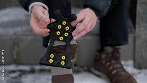 Hands putting ice spikes on slippery shoes for better grip on ice, close up photo