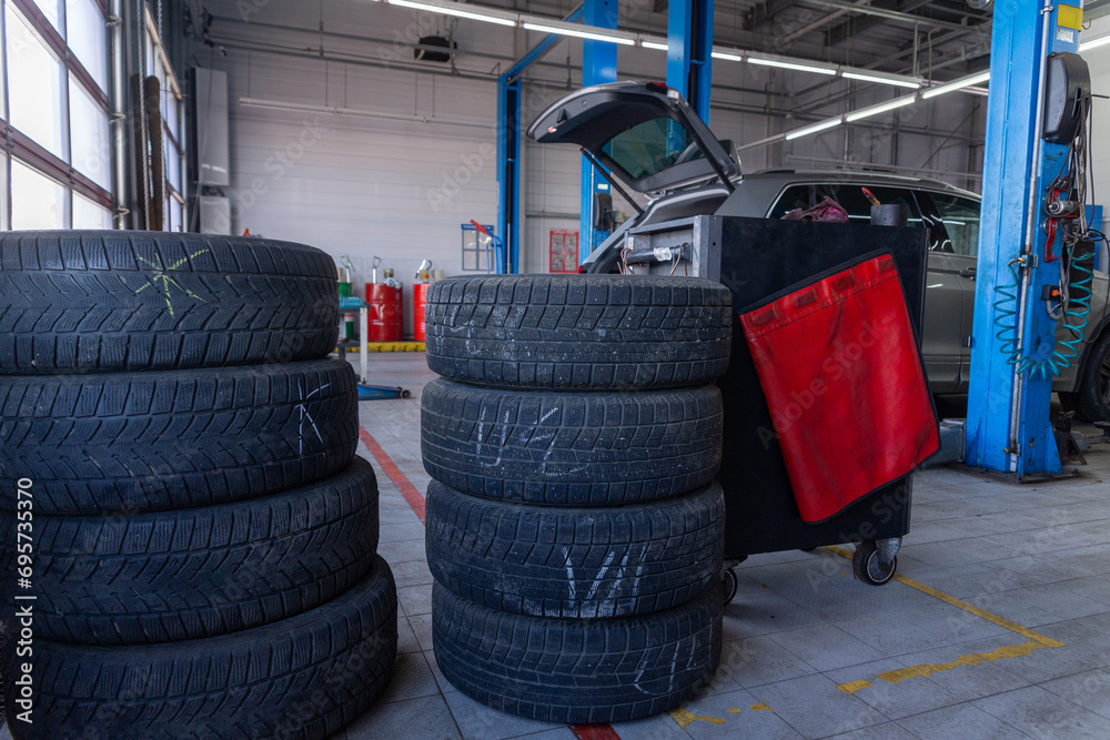A set of tires for seasonal replacement near the lift in the tire workshop. A set of tires for seasonal replacement near the lift in the tire workshop.
