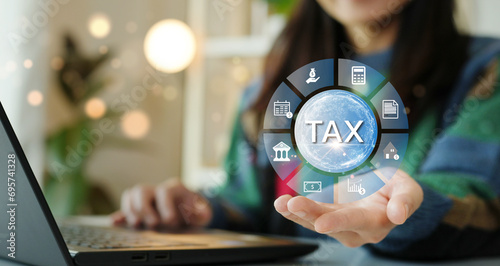 The concept of calculating taxes to be paid. Woman using computer to calculate tax through website and having headache paying taxes.