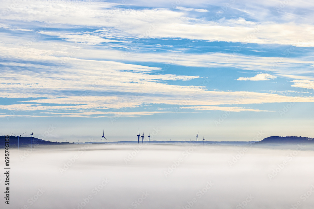 Wind turbines in the fog between two hills