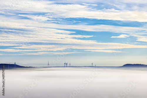 Wind turbines in the fog between two hills