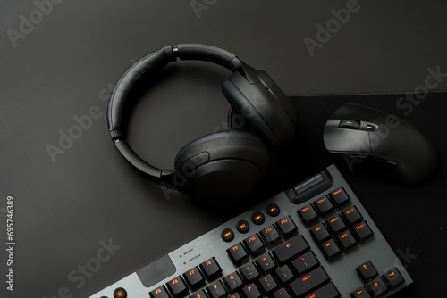 Headphones, computer mouse and keyboard on black background photo
