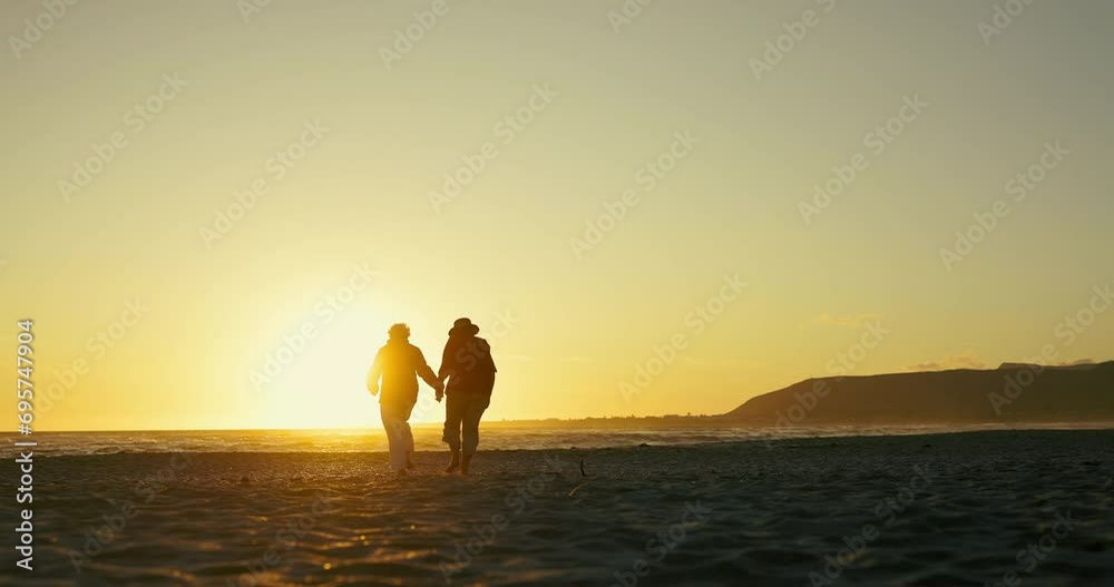 Sunset beach walk, holding hands and senior couple in nature with love, support or adventure together. Sunrise, travel or old people at the ocean for bonding in retirement, vacation or summer holiday Sunset beach walk, holding hands and senior couple in nature with love, support or adventure together. Sunrise, travel or old people at the ocean for bonding in retirement, vacation or summer holiday
