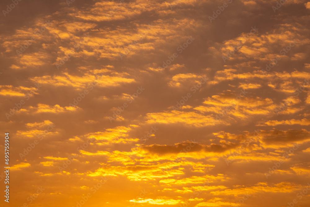 Beautiful nature morning with orange, yellow sunshine and fluffy clouds. Beautiful colorful dramatic sky with clouds at sunset or sunrise.
