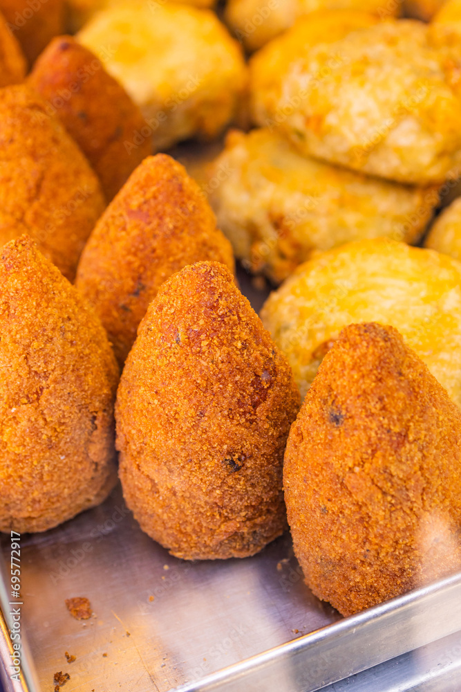 Arancino di riso fritto e frittatine di pasta fritte tradizionali napoletane in una vetrina da vendita di una pizzeria e pronti per essere venduti Arancino di riso fritto e frittatine di pasta fritte tradizionali napoletane in una vetrina da vendita di una pizzeria e pronti per essere venduti