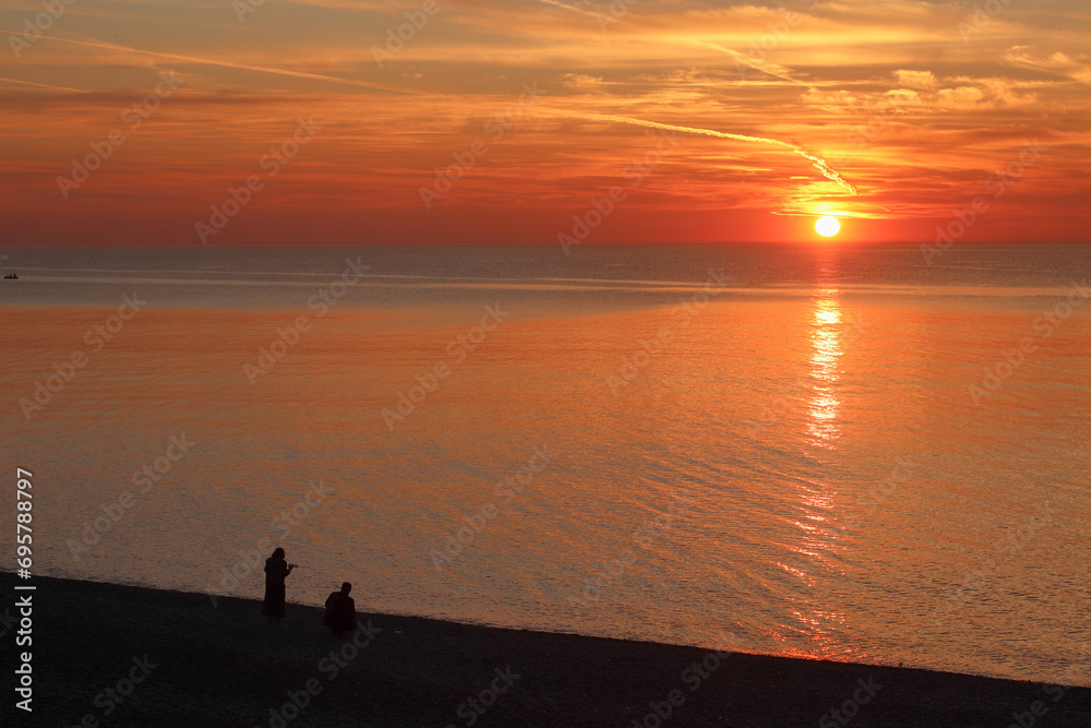 Sunrise on the Black Sea coast with silhouettes of people in Kobuleti, Georgia