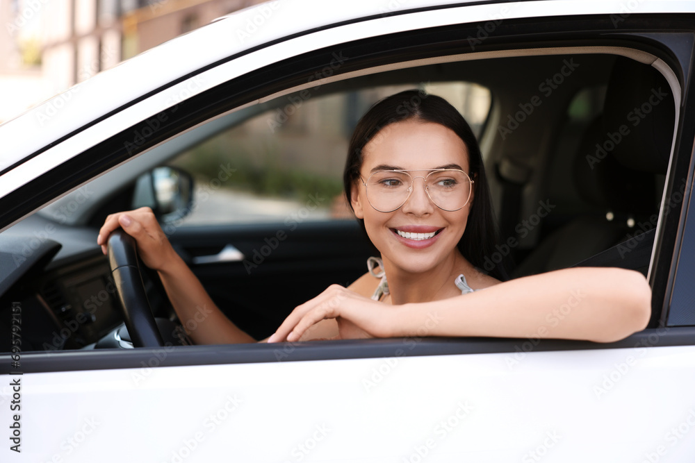 Enjoying trip. Happy young woman in car, view from outside