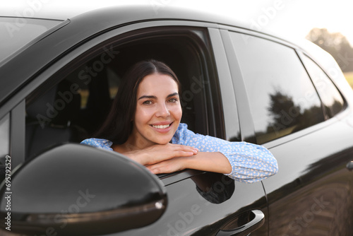 Enjoying trip. Portrait of beautiful happy woman in car, view from outside