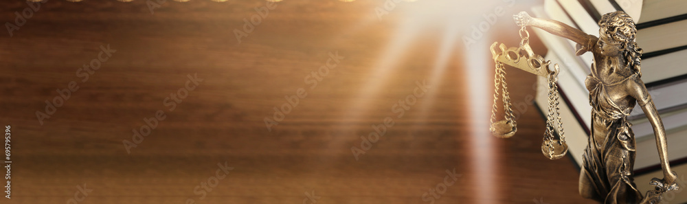 Symbol of fair treatment under law. Figure of Lady Justice and books on wooden table. Banner design with space for text Symbol of fair treatment under law. Figure of Lady Justice and books on wooden table. Banner design with space for text
