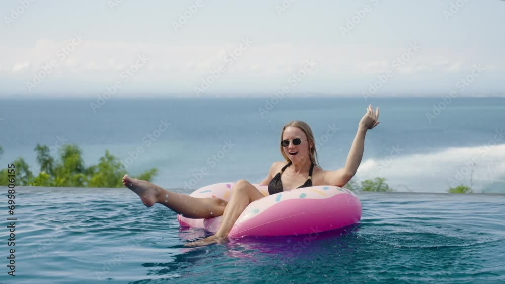 Woman in bikini chill swim on inflatable mattress donut in ocean view infinity pool in luxury private villa. Sunbathing, enjoy on summer vacation trip, rest relax, have fun Woman in bikini chill swim on inflatable mattress donut in ocean view infinity pool in luxury private villa. Sunbathing, enjoy on summer vacation trip, rest relax, have fun