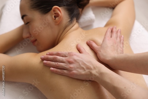 Woman receiving back massage on couch in spa salon, focus on hands