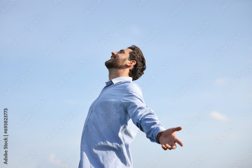 Happy man enjoying feeling of freedom against sky outdoors Happy man enjoying feeling of freedom against sky outdoors