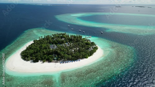 Tropical Island Paradise - Malahini Kuda Bandos, Maldives: Aerial drone anticlockwise rotate and pull out, neighbouring reef backdrop photo