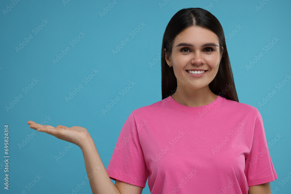 Special promotion. Happy woman holding something on light blue background Special promotion. Happy woman holding something on light blue background