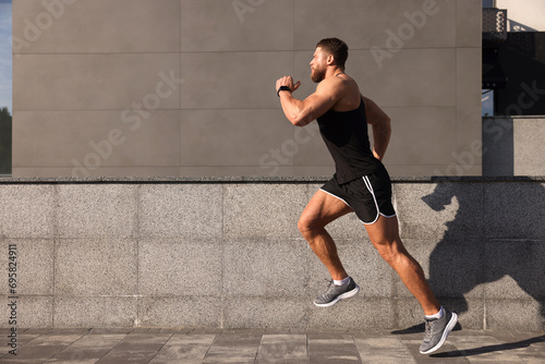 Young man running near building outdoors. Space for text