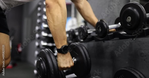Male hands take dumbbells for bodybuilding in gym. Closeup sportsman hands taking weight lifting in sport club photo