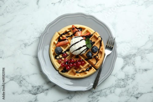 Delicious Belgian waffles with ice cream, berries and chocolate sauce on light marble table, top view